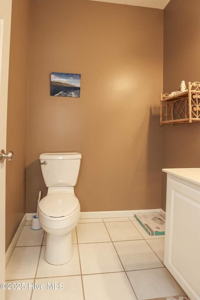 half bath featuring toilet, vanity, tile patterned floors, and baseboards