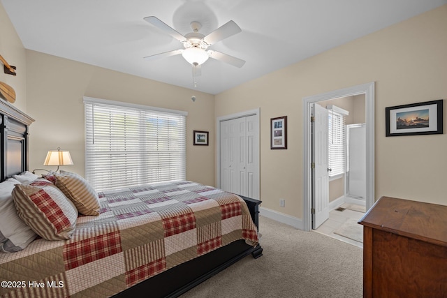 bedroom with a ceiling fan, a closet, light carpet, baseboards, and ensuite bath