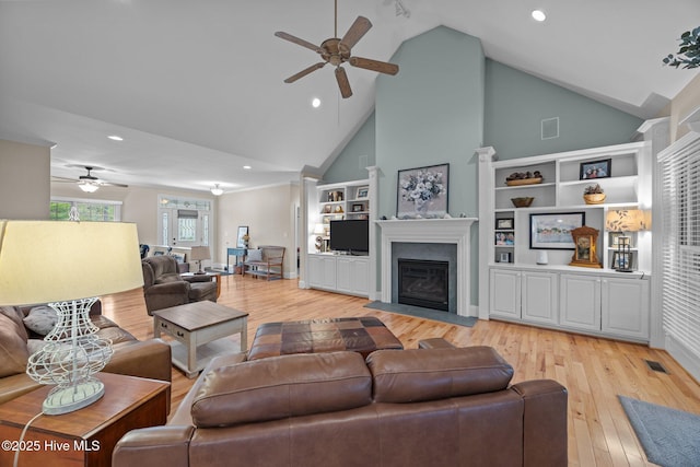 living area featuring a fireplace with flush hearth, light wood-type flooring, high vaulted ceiling, and ceiling fan