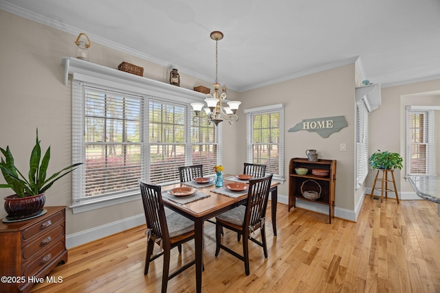 dining area with light wood-style floors, ornamental molding, baseboards, and a notable chandelier