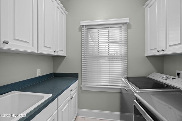 clothes washing area featuring cabinet space, baseboards, a sink, and washer and clothes dryer
