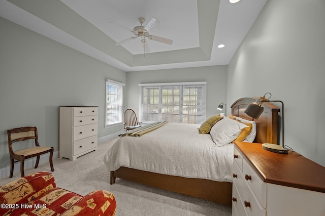 bedroom featuring recessed lighting, a raised ceiling, a ceiling fan, baseboards, and light colored carpet
