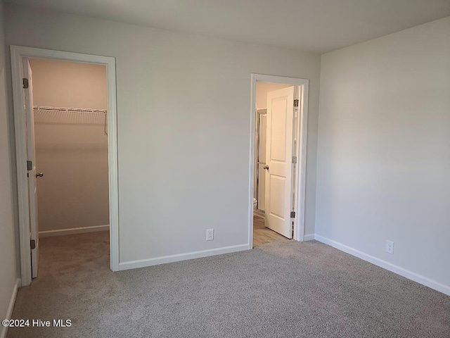 460 Maides Ave, Wilmington, NC 28405 - unfurnished bedroom with a closet, baseboards, carpet, and a walk in closet