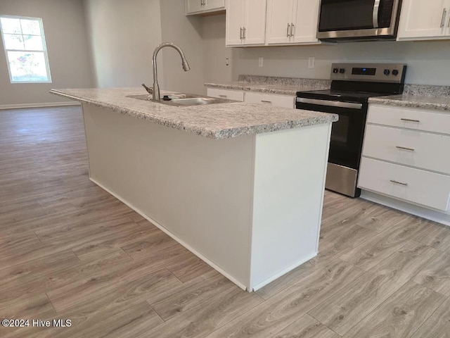 kitchen featuring light wood-style flooring, white cabinetry, a kitchen island with sink, appliances with stainless steel finishes, and a sink