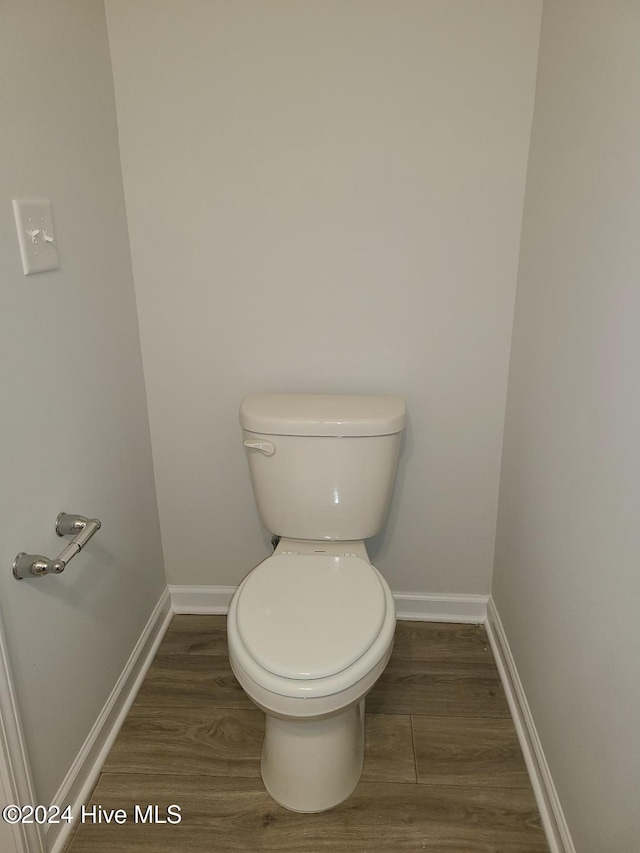 bathroom with toilet, baseboards, and wood finished floors