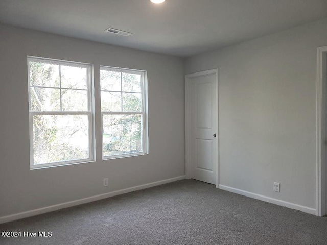 carpeted spare room featuring baseboards and visible vents