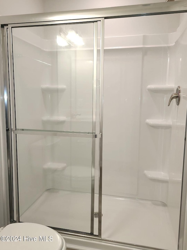 bathroom featuring toilet and a stall shower