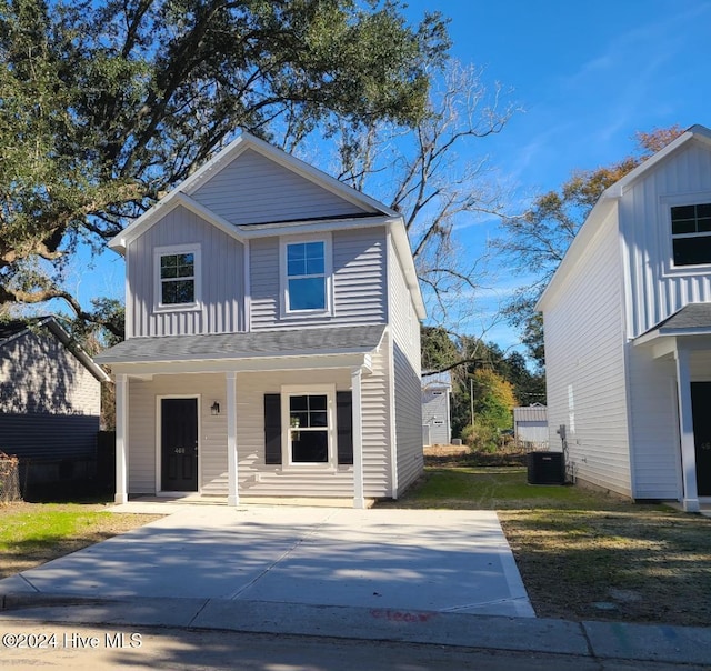 view of front of home with board and batten siding, a porch, a front lawn, and central air condition unit