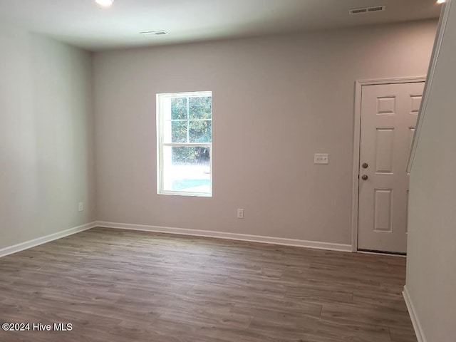 empty room featuring wood finished floors, baseboards, and visible vents
