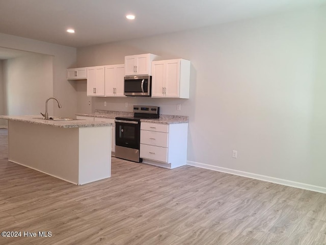 kitchen featuring light wood-type flooring, white cabinets, recessed lighting, appliances with stainless steel finishes, and a sink