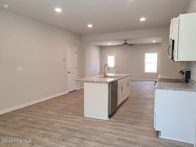 kitchen featuring a sink, appliances with stainless steel finishes, white cabinetry, light wood finished floors, and a center island with sink