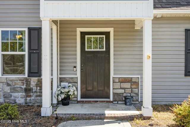 500 Maggies Ct, Jacksonville, NC 28540 - entrance to property featuring roof with shingles, stone siding, and covered porch