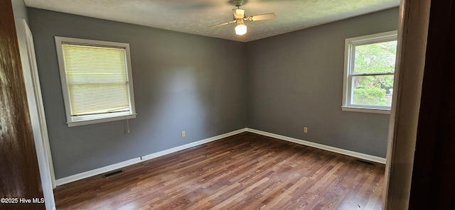 unfurnished room with visible vents, a ceiling fan, dark wood-style floors, and baseboards