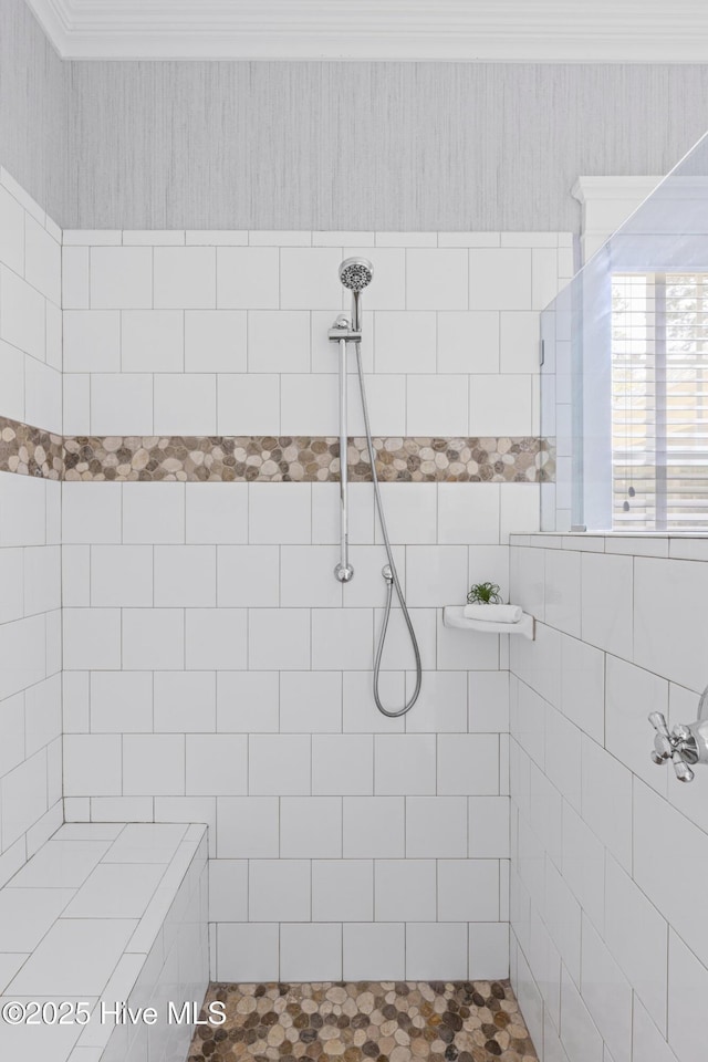 full bathroom featuring a tile shower and ornamental molding