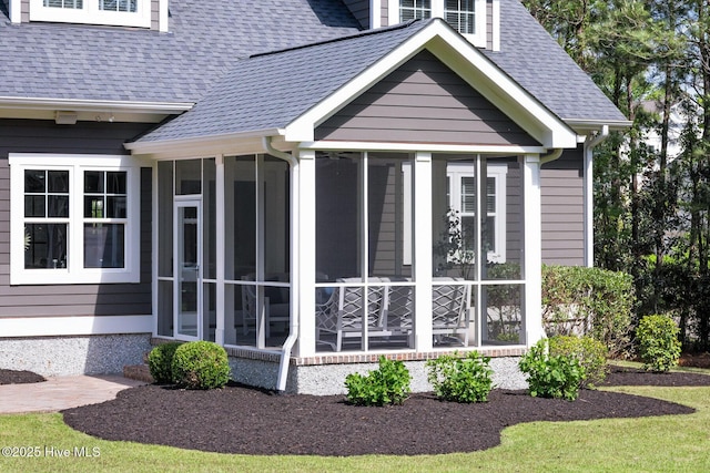 back of property with a yard, a sunroom, and roof with shingles