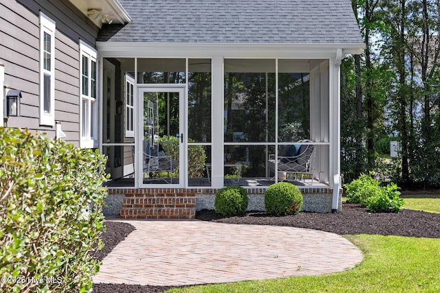 view of side of property featuring a sunroom and roof with shingles