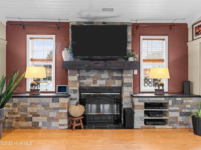 433 Dion Dr, Hubert, NC 28539 - living room featuring wood finished floors, a wealth of natural light, a stone fireplace, and visible vents