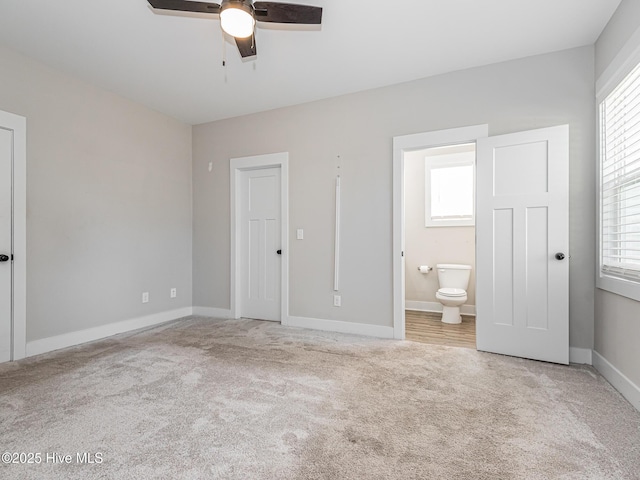 unfurnished bedroom with baseboards, ensuite bath, carpet floors, and ceiling fan