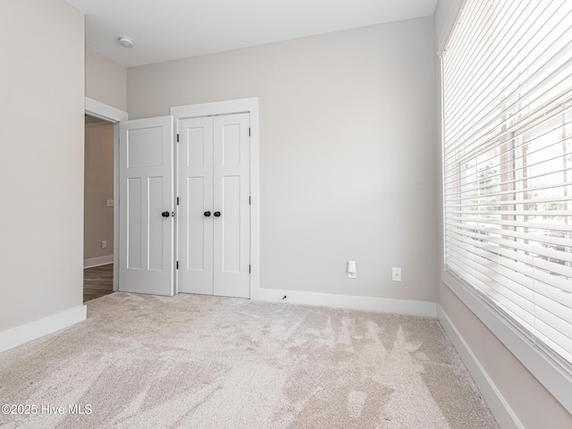 unfurnished bedroom with baseboards, carpet flooring, and a closet