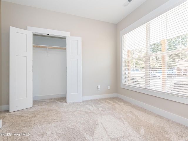 unfurnished bedroom with baseboards, carpet floors, a closet, and multiple windows