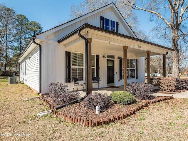 modern farmhouse with a front lawn, a porch, and cooling unit