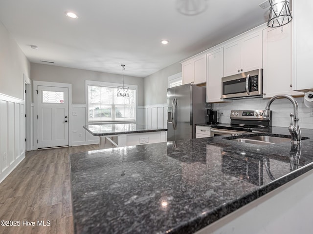 kitchen featuring white cabinets, stainless steel appliances, a sink, an inviting chandelier, and decorative backsplash