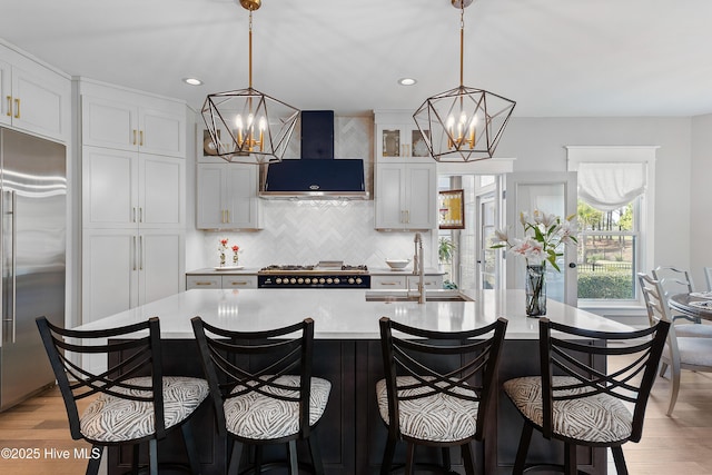 2592 St James Dr SE, Southport, NC 28461 - kitchen featuring stainless steel built in fridge, a chandelier, a sink, wall chimney range hood, and recessed lighting
