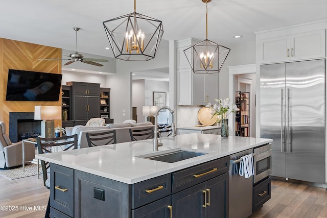2592 St James Dr SE, Southport, NC 28461 - kitchen with stainless steel appliances, a sink, white cabinetry, light wood-style flooring, and recessed lighting