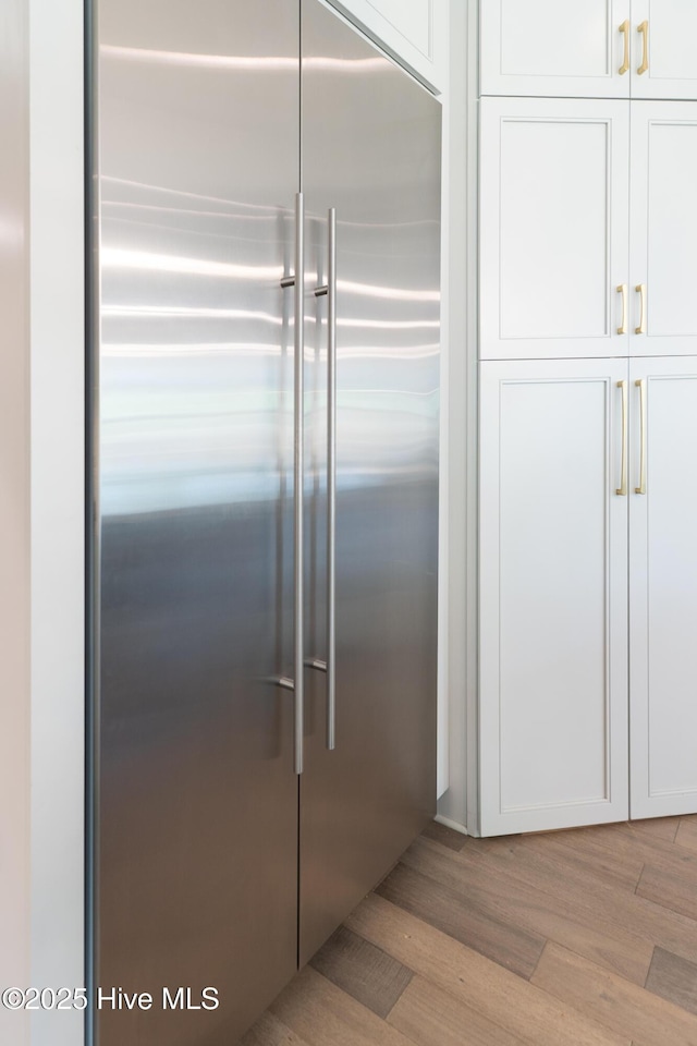 2592 St James Dr SE, Southport, NC 28461 - detailed view of stainless steel built in refrigerator, wood finished floors, and white cabinets