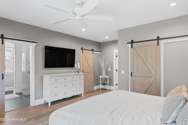 2592 St James Dr SE, Southport, NC 28461 - bedroom featuring a barn door, recessed lighting, wood finished floors, baseboards, and ceiling fan