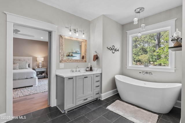 2592 St James Dr SE, Southport, NC 28461 - ensuite bathroom featuring vanity, a freestanding bath, baseboards, and a ceiling fan