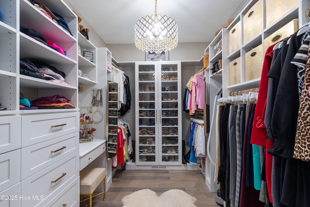 2592 St James Dr SE, Southport, NC 28461 - walk in closet featuring a chandelier and wood finished floors