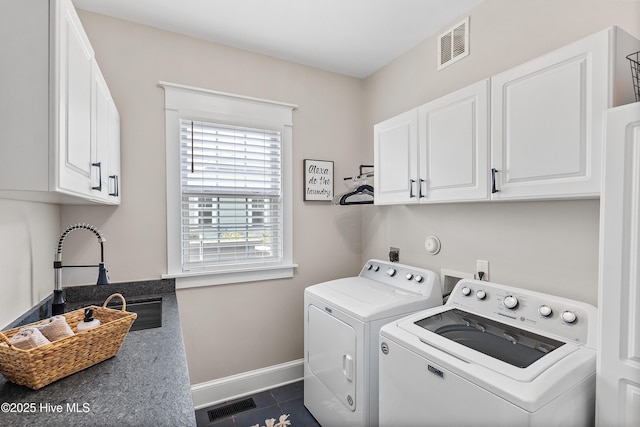 2592 St James Dr SE, Southport, NC 28461 - washroom featuring washing machine and dryer, cabinet space, baseboards, and dark tile patterned flooring