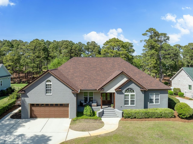 2592 St James Dr SE, Southport, NC 28461 - ranch-style home with concrete driveway, a porch, a front lawn, an attached garage, and roof with shingles