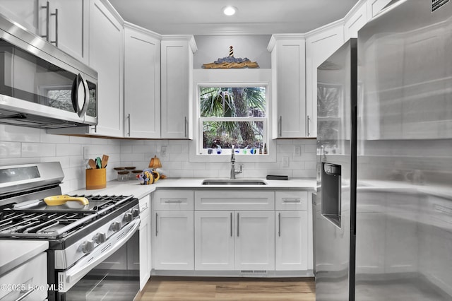 kitchen featuring white cabinets, stainless steel appliances, light countertops, and a sink