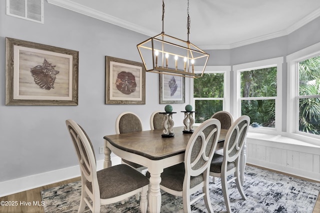 dining room featuring wood finished floors, visible vents, ornamental molding, baseboards, and a notable chandelier