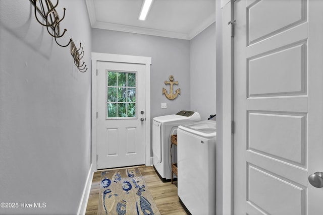 laundry area featuring laundry area, washing machine and dryer, crown molding, baseboards, and light wood-style flooring