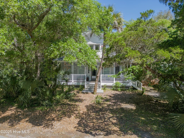 view of property hidden behind natural elements featuring covered porch