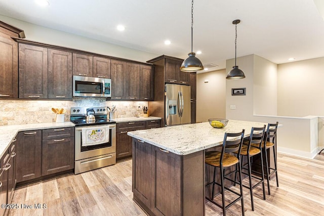 20 Barkley Ln, Pinehurst, NC 28374 - kitchen with a kitchen breakfast bar, dark brown cabinetry, light wood-style floors, stainless steel appliances, and a kitchen island