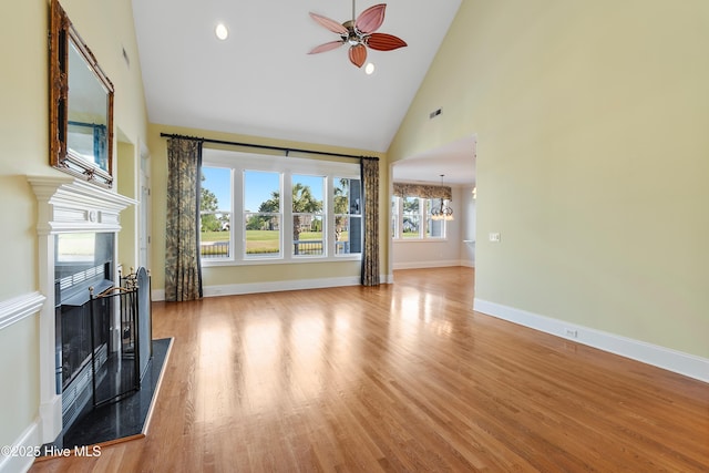 3675 W Medinah Ave, Southport, NC 28461 - unfurnished living room with a fireplace, high vaulted ceiling, ceiling fan with notable chandelier, baseboards, and wood finished floors