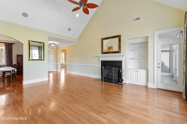 3675 W Medinah Ave, Southport, NC 28461 - unfurnished living room with arched walkways, high vaulted ceiling, built in shelves, a ceiling fan, and visible vents
