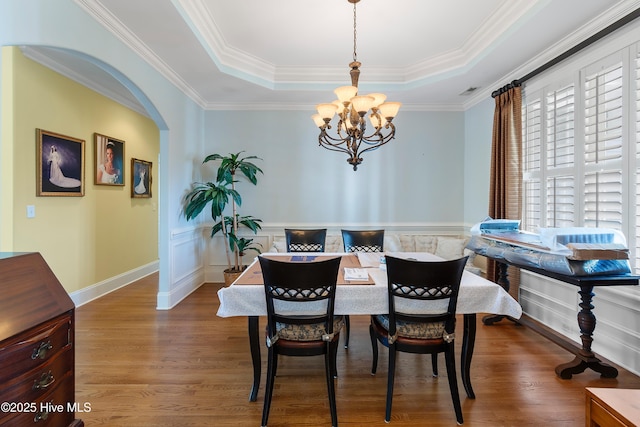 3675 W Medinah Ave, Southport, NC 28461 - dining room with arched walkways, a tray ceiling, a notable chandelier, and wood finished floors