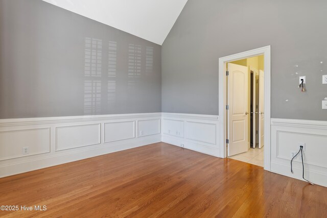 3675 W Medinah Ave, Southport, NC 28461 - empty room with vaulted ceiling, wainscoting, wood finished floors, and a decorative wall