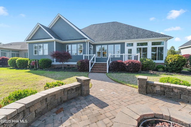 3675 W Medinah Ave, Southport, NC 28461 - view of front facade featuring a shingled roof, crawl space, a fire pit, and a front yard