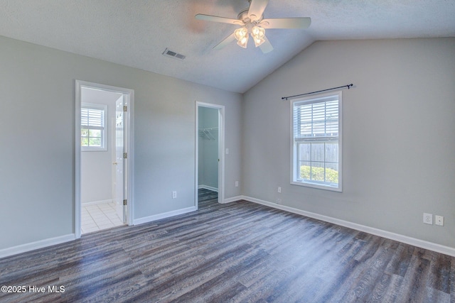2715 Ashby Dr, Wilmington, NC 28411 - unfurnished bedroom with wood finished floors, visible vents, vaulted ceiling, a walk in closet, and a textured ceiling