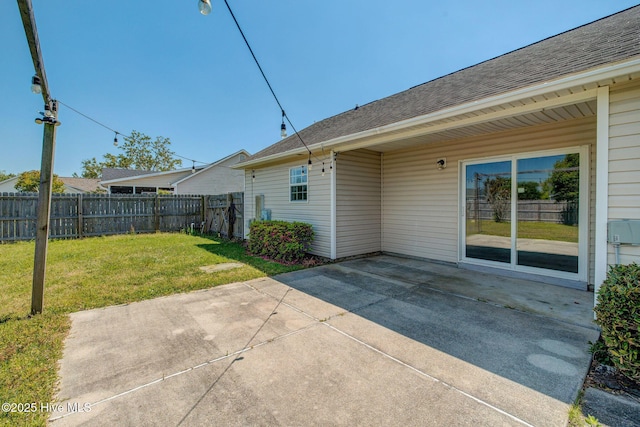 2715 Ashby Dr, Wilmington, NC 28411 - rear view of property featuring fence, a lawn, roof with shingles, and a patio