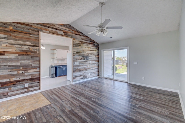 2715 Ashby Dr, Wilmington, NC 28411 - unfurnished living room with lofted ceiling, wooden walls, wood finished floors, a textured ceiling, and ceiling fan