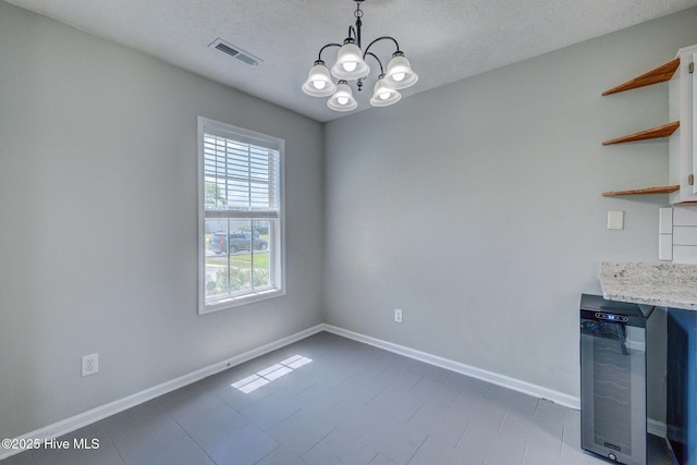 2715 Ashby Dr, Wilmington, NC 28411 - unfurnished dining area featuring a textured ceiling, baseboards, visible vents, a notable chandelier, and beverage cooler