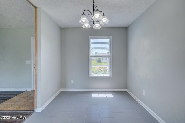 2715 Ashby Dr, Wilmington, NC 28411 - unfurnished dining area with dark tile patterned floors, a textured ceiling, baseboards, and an inviting chandelier
