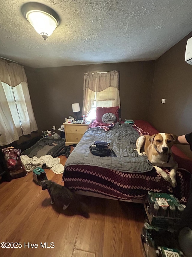 bedroom featuring a textured ceiling, wood finished floors, and multiple windows